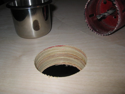 Hole saw cutting cup-holder openings into a wooden poker table raceway